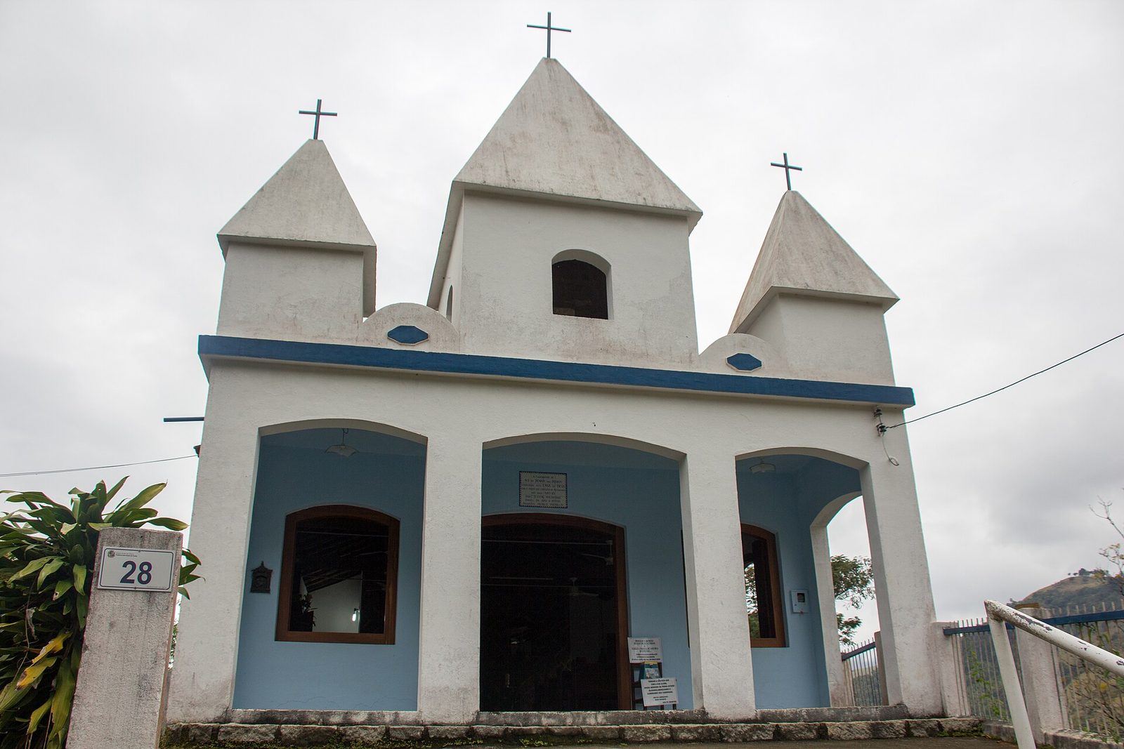 The plain colonial facade of the Penha church, white against the forest.