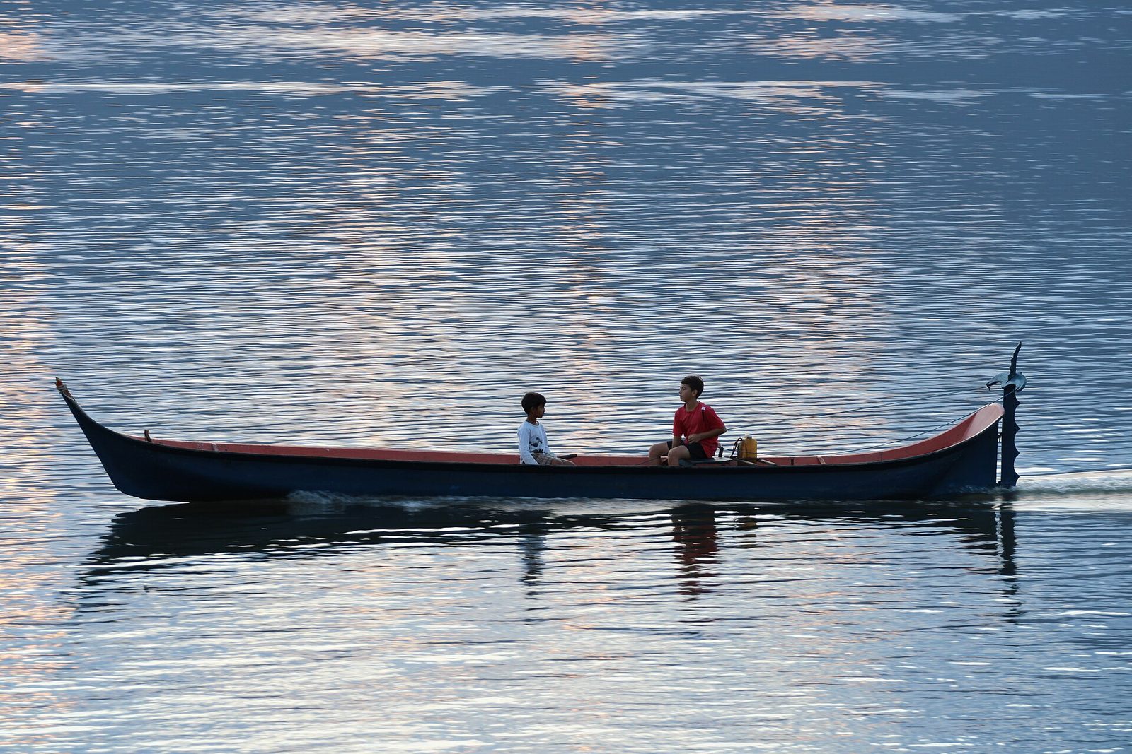A caiçara dugout out on calm water — the old way of crossing the bay and reaching the fishing grounds.
