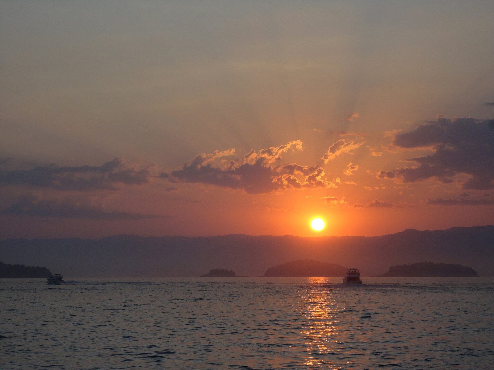Sunset over the island-strewn bay — the reward for an early start is finishing the drive before the light goes.