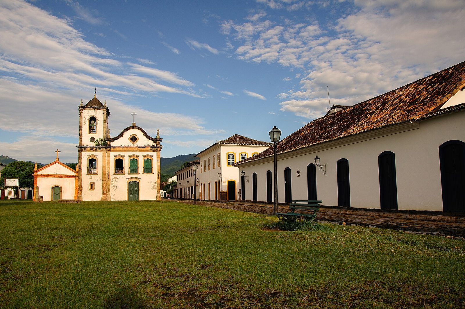 A row of low, whitewashed colonial houses running down toward a church — the everyday fabric of the old town, white walls and colored frames.
