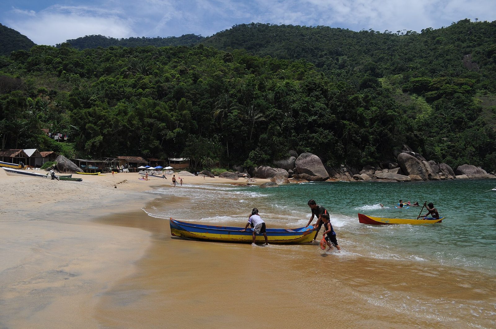 Wooden fishing boats drawn up on the sand at Praia do Sono, with the rocks and forested headland beyond — a working caiçara beach, not a resort.